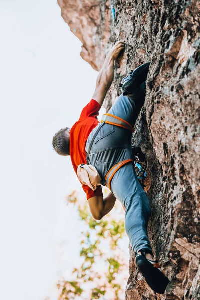 陸上競技のための崖の上の挑戦的な歩道に登る若い男 — ストック写真