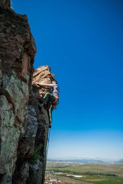 若いです男はバックグラウンドで美しい景色と岩の上に登るリード — ストック写真