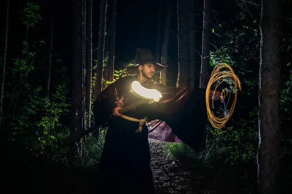 魔法使いの衣装ハロウィンのための木の間に立つ木のスタッフと男を着て — ストック写真