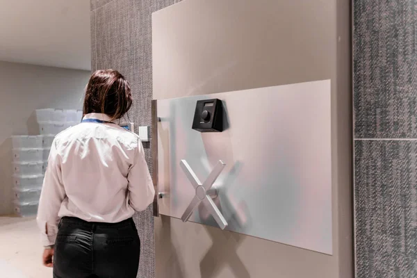 Woman entering codes into various access devices for opening the safe door