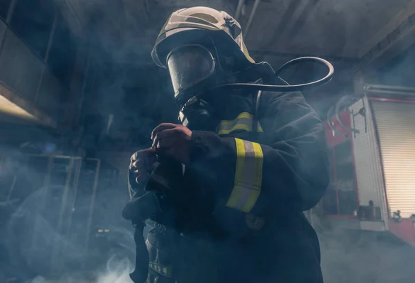 消防士が消防士のターンアウトとヘルメットを着ての肖像画 煙と青の光で暗い背景 — ストック写真