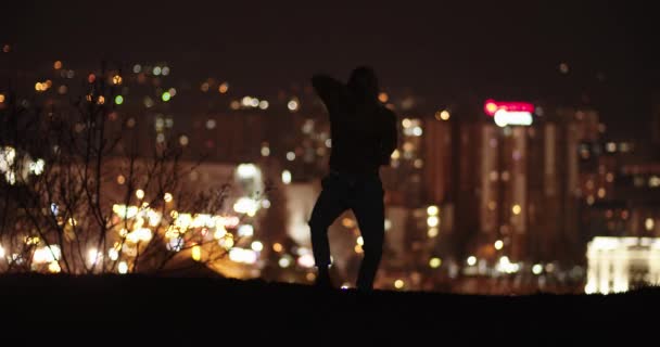 Sylwetka Tancerza Tańczącego Nocy Wzgórzu Przed Światłami Miasta — Wideo stockowe