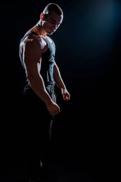 若い筋肉の男の肖像画は暗い背景に彼の筋肉を曲げられている — ストック写真