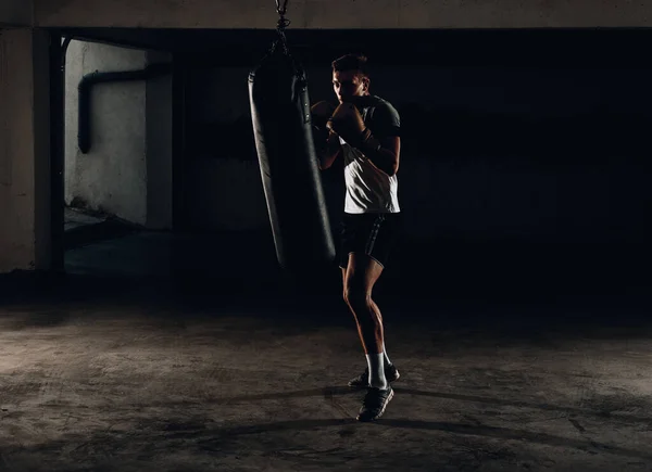 Sterke Kickboxer Man Ponsen Zwarte Zandzak Sportschool Achtergrond — Stockfoto