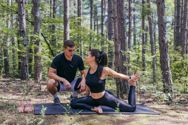 若いアクティブなカップルは ジョギングやランニング後にヨガマットで森の中でストレッチ演習を行う — ストック写真