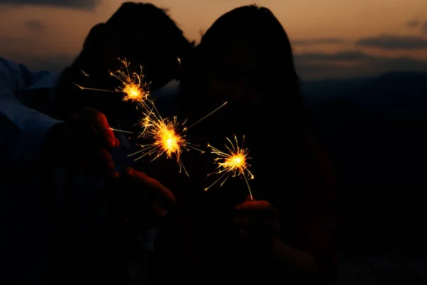 シルエット女性と男を保持燃焼輝く花火ベンガルライト — ストック写真