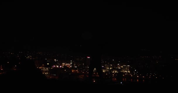 街の明かりの前の丘の上で夜に踊る男性ダンサーのシルエット 低キーの映像 — ストック動画