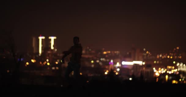 Silhuett Manlig Dansare Som Dansar Natten Uppe Kullen Framför Stadsljuset — Stockvideo