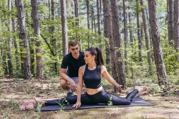 Joven Pareja Activa Haciendo Ejercicios Estiramiento Bosque Una Esterilla Yoga — Foto de Stock