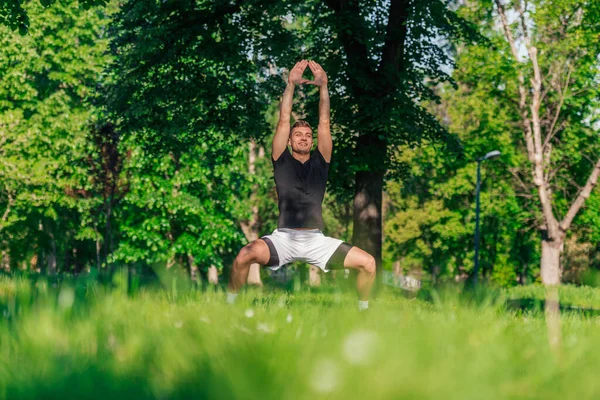 Young Man Practices Yoga Variations Goddess Pose Outdoor Park — Stock Photo, Image