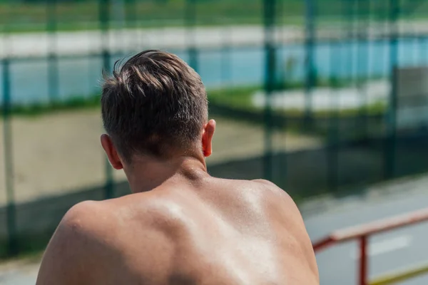 Vista Posterior Atleta Masculino Fuerte Sin Una Camisa Sentada Parque —  Fotos de Stock