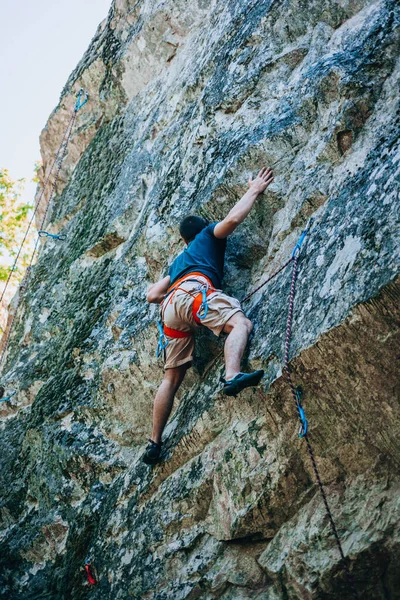 強いスポーティフィットの男性の肖像夏の時間に大きな自然の岩を登っている — ストック写真