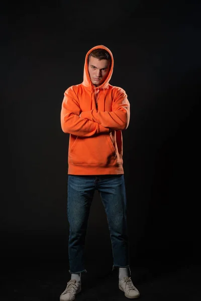 Junger Schöner Mann Jeans Und Orangefarbenem Kapuzenpulli Posiert Vor Schwarzem — Stockfoto