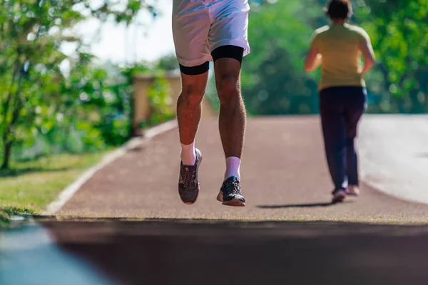 跑道上慢跑的运动员的跑鞋和强壮的运动腿紧跟在脚上 — 图库照片