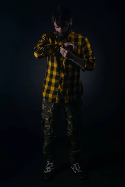 Ciemny Obraz Brodatego Mężczyzny Tatuażami Mocującymi Guziki Żółtej Czarnej Koszuli — Zdjęcie stockowe