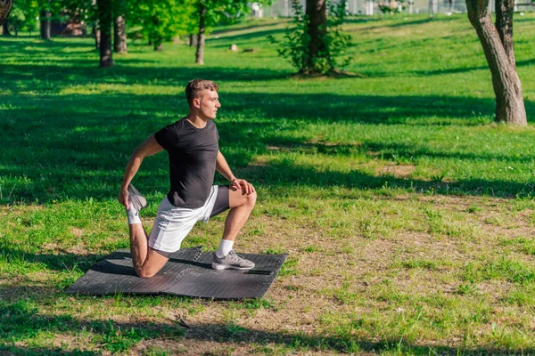 公園でワークアウトをしながら 足を伸ばし 前方の肺を行うスポーティ若い男 — ストック写真