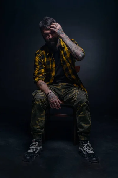 Przystojny Mężczyzna Model Tatuażami Koszulą Tartan Siedzi Krześle Dotyka Jego — Zdjęcie stockowe