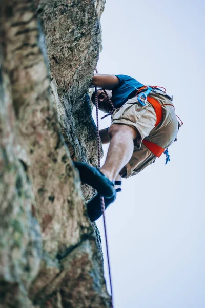 Jongeman Klimmend Een Muur Met Blauwe Lucht Achtergrond — Stockfoto