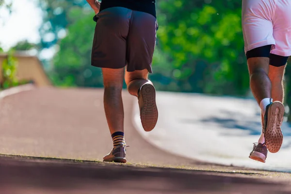 ランニングシューズで足を閉じ ランニングトラックでジョギングするスポーツマンの強い運動脚 — ストック写真