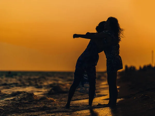 ビーチで楽しんで踊っている陽気な若い女性の屋外ショット 夕暮れ時に海沿いで遊ぶ女友達 — ストック写真
