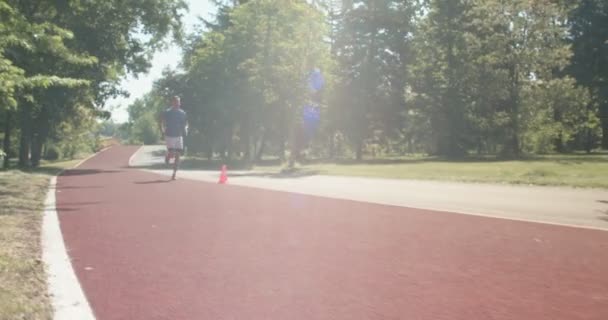 陸上競技トラックでスプリント列車を実行しているブロンドの男性アスリート 激しいスプリント運動でマラソンランナー — ストック動画