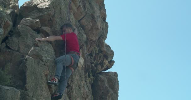 在阳光灿烂的山中爬上岩石的男性登山者 — 图库视频影像