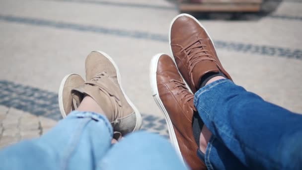The feet of tourists are resting on the bench. Male and female legs in boots — Stock Video