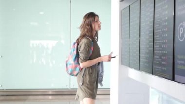 Güzel genç turist kızla sırt çantası ve uçuş bilgi yönetim kurulu yakın Uluslararası Havaalanı Bagaj devam
