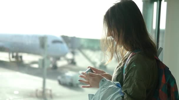 フライト - 美しい少女を待っている空港のターミナルで飛行機の写真を撮る — ストック動画