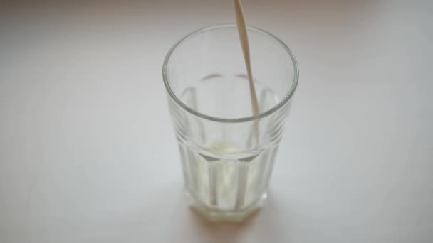 Plan au ralenti de verser un verre de lait sur un fond blanc .