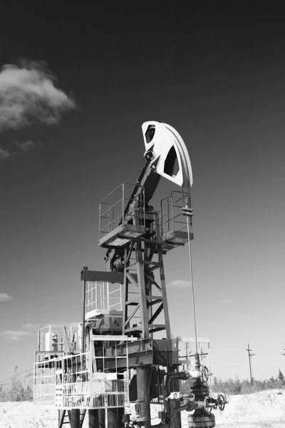Oil and gas industry. Work of oil pump jack on a oil field in desert. Black and white photo