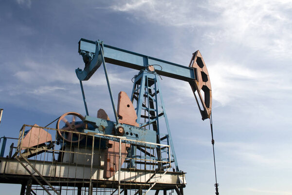 Нефтегазовая промышленность. Работа нефтяного насоса на нефтяном месторождении. Голубое небо
