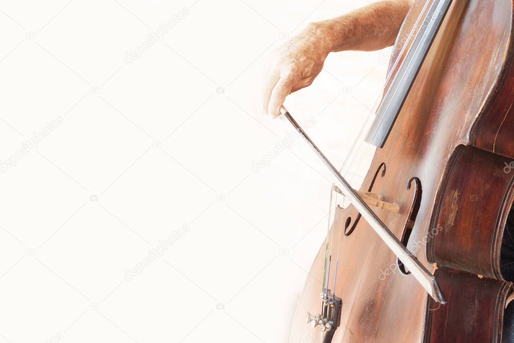 Part of the double bass with bow and hand musician on Belon background.