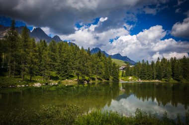 Trentino 'daki San Pellegrino gölünün yaz manzarası. Suları Val di Fassa ve Cime di Passo San Pellegrino 'nun muhteşem Dolomitlerini yansıtıyor. 