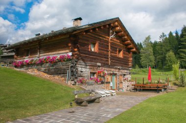 Bellamonte, İtalya - 20 Temmuz 2020: Bellamonte 'nin merkezinde çiçekli tipik dağ ahşabı kulübe, Trentino Alto-Adige, İtalya