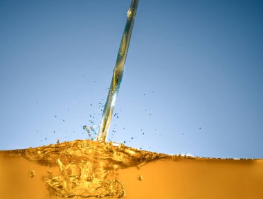 Close-up of oil and liquid pouring on dark background. clipart
