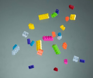 Gri arka plan üzerine düşen renkli oyuncak tuğla yığını
