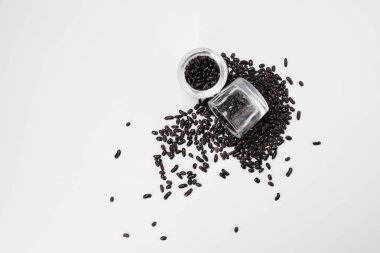 Beyaz zemin üzerinde bir cam kavanoza dağınık bir fasulye üstten görünüm