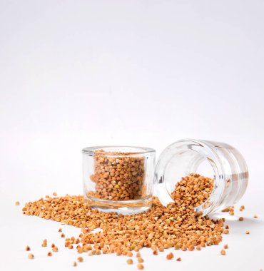 beyaz zemin üzerinde bir cam kavanoza bir dağınık yulaf taneleri üstten görünüm