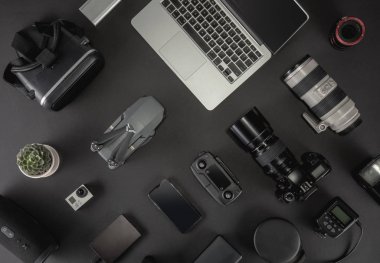 Çalışma alanı fotoğrafçı ile dizüstü bilgisayar, dijital kamera, bellek kartı, kamera, dron, uzaktan kumanda, telefon, Vr gözlük ve Fotoğrafçılık. Üstten görünüm siyah tablo arka plan üzerinde. Mockup şablon kavramı.