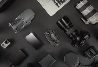 Çalışma alanı fotoğrafçı ile dizüstü bilgisayar, dijital kamera, bellek kartı, kamera, dron, uzaktan kumanda, telefon, Vr gözlük ve Fotoğrafçılık. Üstten görünüm siyah tablo arka plan üzerinde. Mockup şablon kavramı.