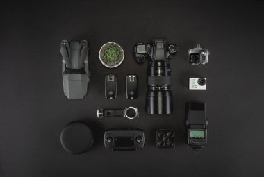 Çalışma alanı fotoğrafçı ile dizüstü bilgisayar, dijital kamera, bellek kartı, kamera, dron, uzaktan kumanda, telefon, Vr gözlük ve Fotoğrafçılık. Üstten görünüm siyah tablo arka plan üzerinde. Mockup şablon kavramı.