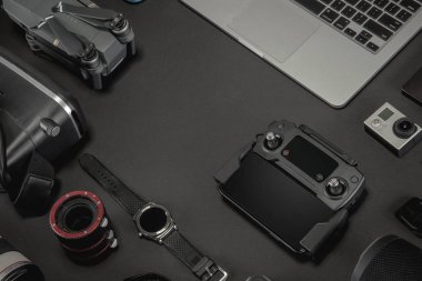 Çalışma alanı fotoğrafçı ile dizüstü bilgisayar, dijital kamera, bellek kartı, kamera, dron, uzaktan kumanda, telefon, Vr gözlük ve Fotoğrafçılık. Üstten görünüm siyah tablo arka plan üzerinde. Mockup şablon kavramı.