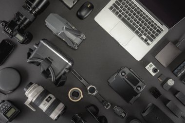 Çalışma alanı fotoğrafçı ile dizüstü bilgisayar, dijital kamera, bellek kartı, kamera, dron, uzaktan kumanda, telefon, Vr gözlük ve Fotoğrafçılık. Üstten görünüm siyah tablo arka plan üzerinde. Mockup şablon kavramı.