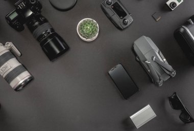Çalışma alanı fotoğrafçı ile dizüstü bilgisayar, dijital kamera, bellek kartı, kamera, dron, uzaktan kumanda, telefon, Vr gözlük ve Fotoğrafçılık. Üstten görünüm siyah tablo arka plan üzerinde. Mockup şablon kavramı.