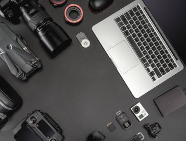 Çalışma alanı fotoğrafçı ile dizüstü bilgisayar, dijital kamera, bellek kartı, kamera, dron, uzaktan kumanda, telefon, Vr gözlük ve Fotoğrafçılık. Üstten görünüm siyah tablo arka plan üzerinde. Mockup şablon kavramı.