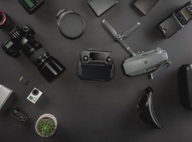 Çalışma alanı fotoğrafçı ile dizüstü bilgisayar, dijital kamera, bellek kartı, kamera, dron, uzaktan kumanda, telefon, Vr gözlük ve Fotoğrafçılık. Üstten görünüm siyah tablo arka plan üzerinde. Mockup şablon kavramı.