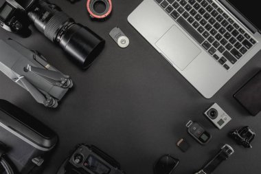 Çalışma alanı fotoğrafçı ile dizüstü bilgisayar, dijital kamera, bellek kartı, kamera, dron, uzaktan kumanda, telefon, Vr gözlük ve Fotoğrafçılık. Üstten görünüm siyah tablo arka plan üzerinde. Mockup şablon kavramı.