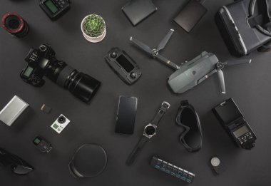 Çalışma alanı fotoğrafçı ile dizüstü bilgisayar, dijital kamera, bellek kartı, kamera, dron, uzaktan kumanda, telefon, Vr gözlük ve Fotoğrafçılık. Üstten görünüm siyah tablo arka plan üzerinde. Mockup şablon kavramı.