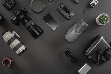 Çalışma alanı fotoğrafçı ile dizüstü bilgisayar, dijital kamera, bellek kartı, kamera, dron, uzaktan kumanda, telefon, Vr gözlük ve Fotoğrafçılık. Üstten görünüm siyah tablo arka plan üzerinde. Mockup şablon kavramı.